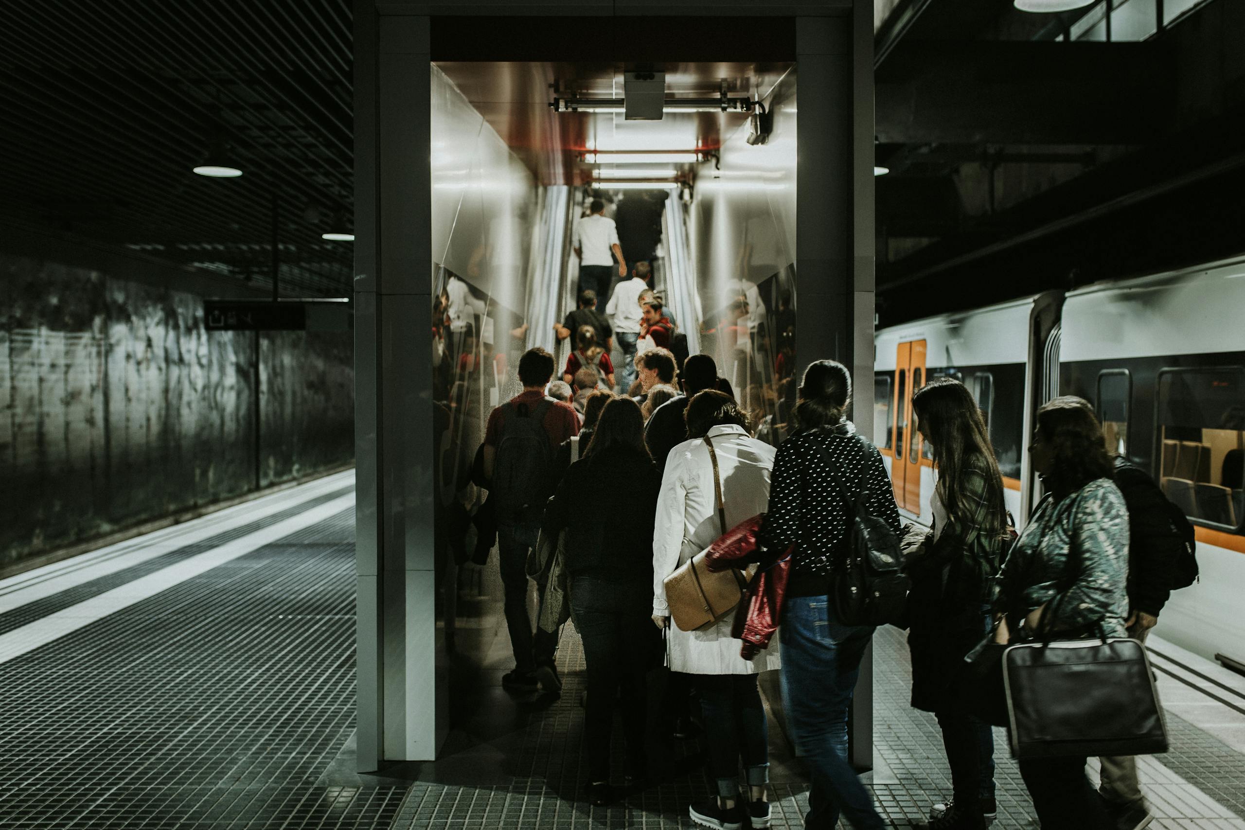 Crowded subway station with people boarding a train in an urban setting, emphasizing public transportation.